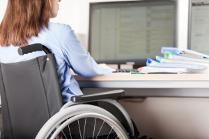 Femme en fauteuil roulant travaillant devant un ordinateur