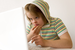 Adolescente porteuse de trisomie 21 travaillant sur un ordinateur portable.